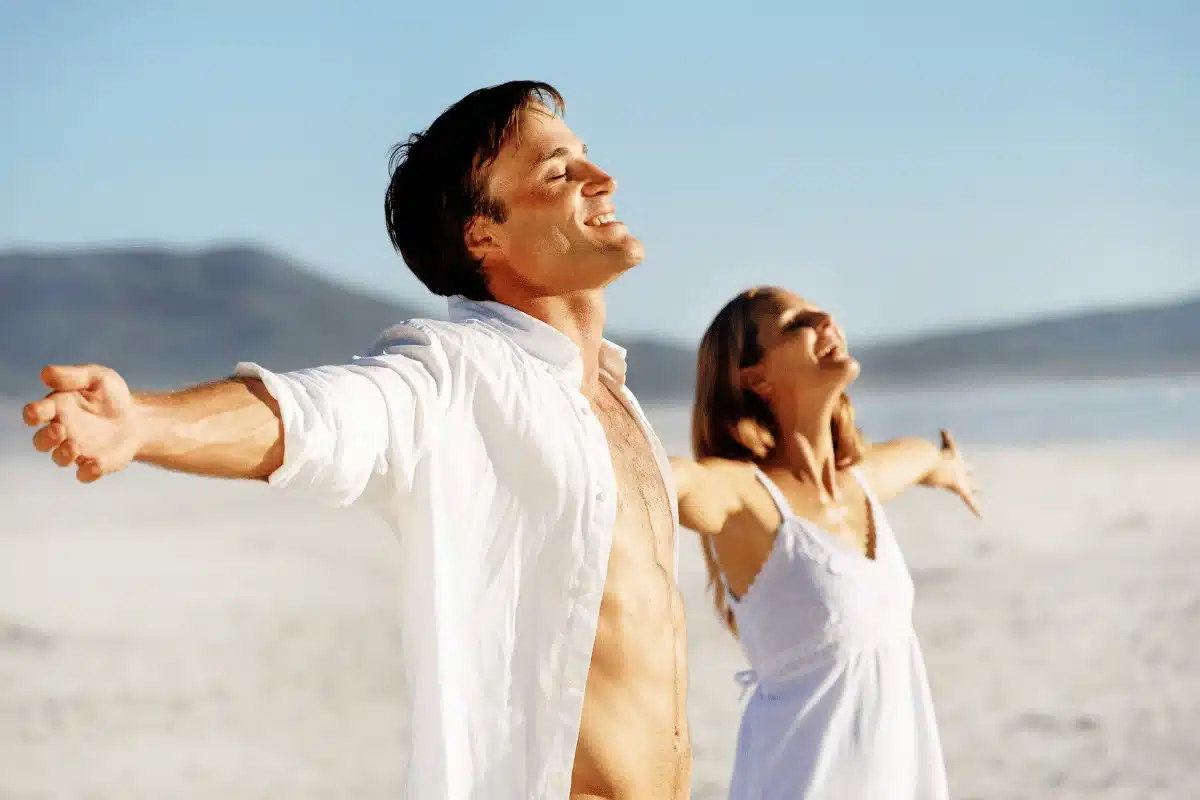 Two people with outstretched arms enjoying the beach.