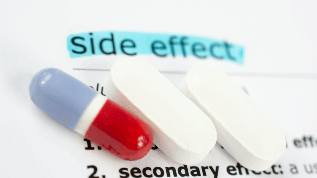 Close-up of a red and blue capsule and two white tablets placed on a document with the words โside effectโ highlighted in blue.