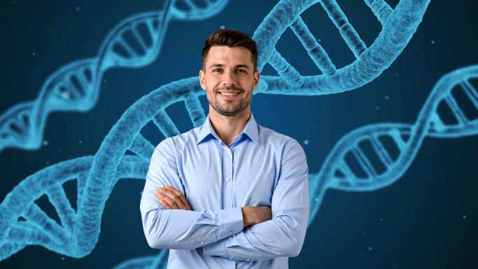 Smiling man in a blue button-down shirt with his arms crossed, standing in front of a dark blue background with abstract, large, blue DNA double helix structures.