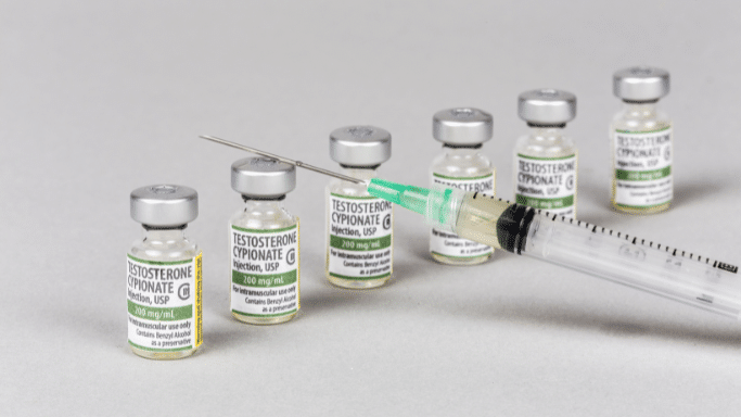 Multiple vials of Testosterone Cypionate arranged in a row next to a medical syringe. Relevant to any discussion where one is asking "does sleep apnea cause low testosterone levels?"