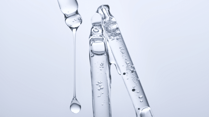Macro shot of multiple glass pipettes dripping clear liquid with small air bubbles.
