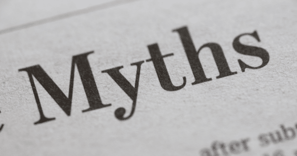 A macro, angled photograph focusing on the word "Myths" printed in a black serif font on textured gray newspaper paper.