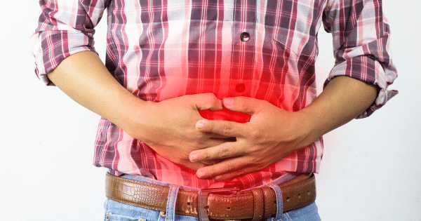 A mid-section view of a person wearing a red and white plaid shirt, clutching their stomach with both hands. A bright red glow is overlaid on the abdominal area.