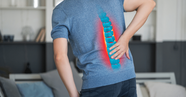 Rear view of a person wearing a blue shirt with a stylized, semi-transparent 3D graphic of a bright blue human spine overlayed on their back. The surrounding spine area glows red, indicating pain or inflammation.