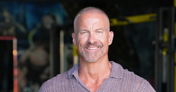 Close-up headshot of a smiling middle-aged man with short graying hair and a trimmed goatee, wearing a knit polo shirt.