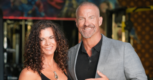 Portrait of a smiling, fit couple posing together in a gym setting.