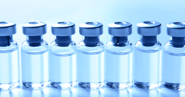 A line of clear glass medicine vials capped with silver tops.