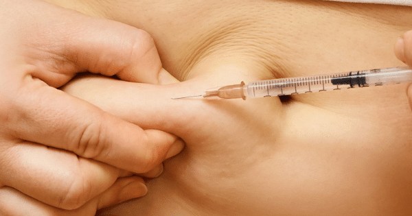 Close-up of a subcutaneous medical injection being administered into pinched skin.
