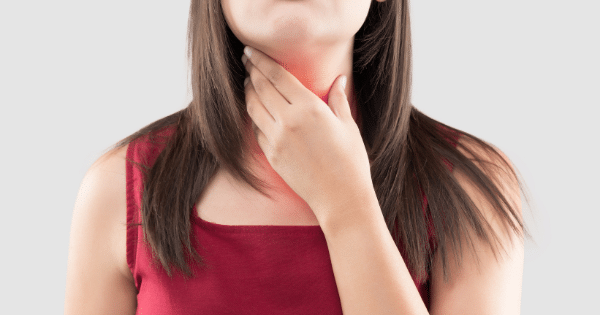 A close-up of a woman with long dark hair holding her hand against her neck, with a glowing red highlight on her throat.