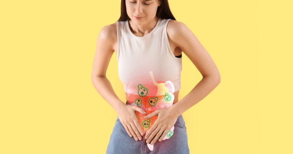 A woman holding her stomach in pain against a yellow background, featuring a stylized graphic overlay of her digestive tract filled with green bacteria microbes.