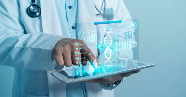 Close-up of a doctor's hand touching a tablet screen that projects a glowing holographic interface featuring a DNA double helix strand and medical vitals bars.