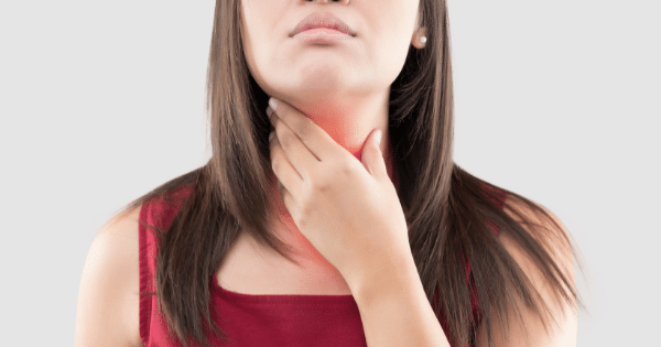 A woman in a red top with her hand placed on her neck, where a red overlay suggests the area of the thyroid gland.