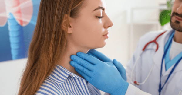 A doctor wearing blue medical gloves performing a physical examination of a female patient's neck, with a medical illustration of a thyroid gland visible in the background.