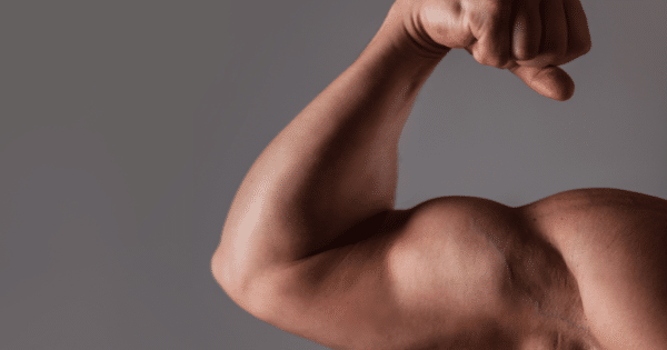 Close-up of a person flexing their bicep against a plain grey background.
