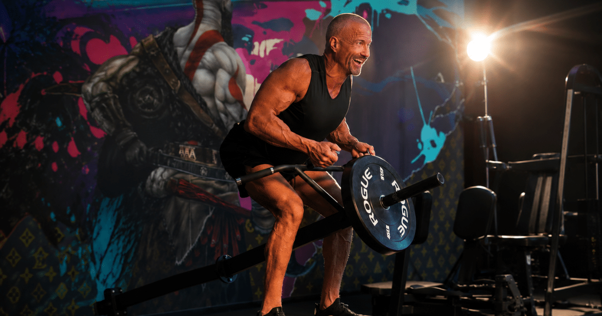 Muscular man using a T-bar row weight machine in a gym setting.