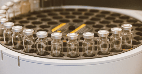 A high-throughput circular automated sample tray loaded with clear glass lab vials.