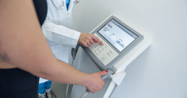 A healthcare provider operating a body composition machine while a patient holds the handheld electrode sensor.