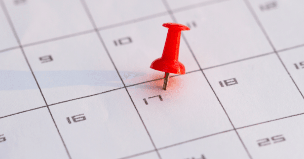Close-up of a calendar grid with a bright red pushpin stuck into the box for the 17th day.