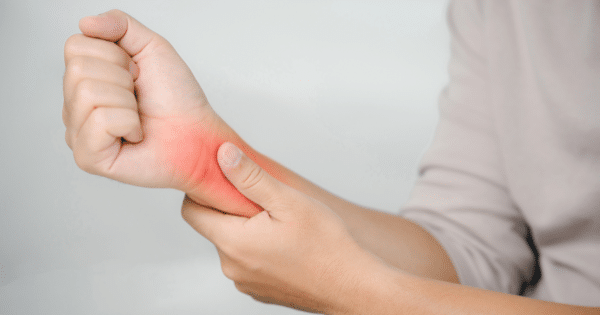A close-up of a person gripping their opposite wrist with glowing red highlighting to indicate pain or inflammation.