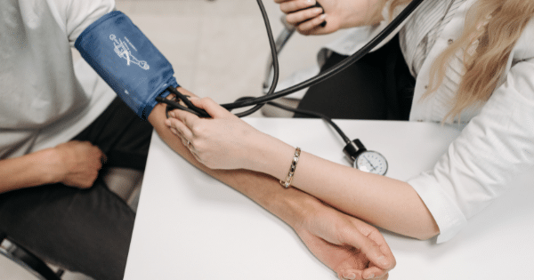 A healthcare provider measuring a patient's blood pressure using a manual sphygmomanometer cuff and gauge.