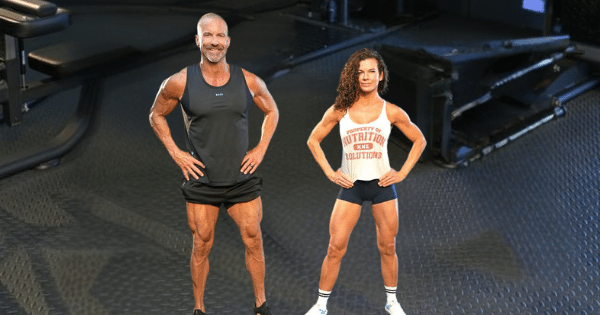 A athletic man and woman with visible muscular definition stand side-by-side with hands on their hips in a gym setting.
