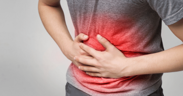 A midsection view of a person holding their stomach in pain, highlighted with a red glowing gradient across the abdominal area.